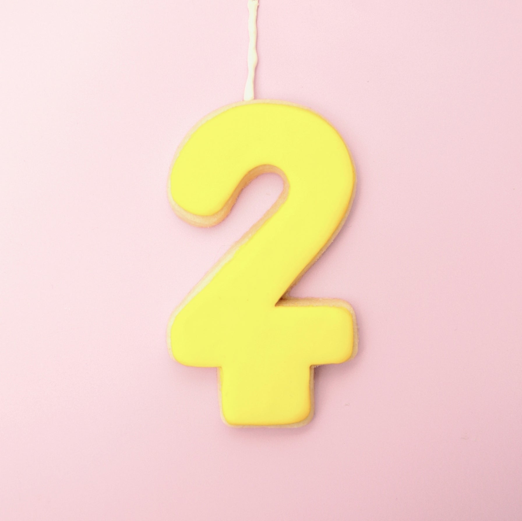 Yellow number '2' cookie on a pink background